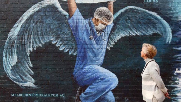 A woman looks at a mural of a nurse with wings  holding a globe on International Nurses Day, Australia
