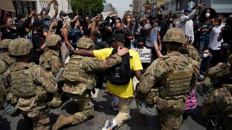 Protestanter och militär knäböjer tillsammans under denmonstrationen mot rasism