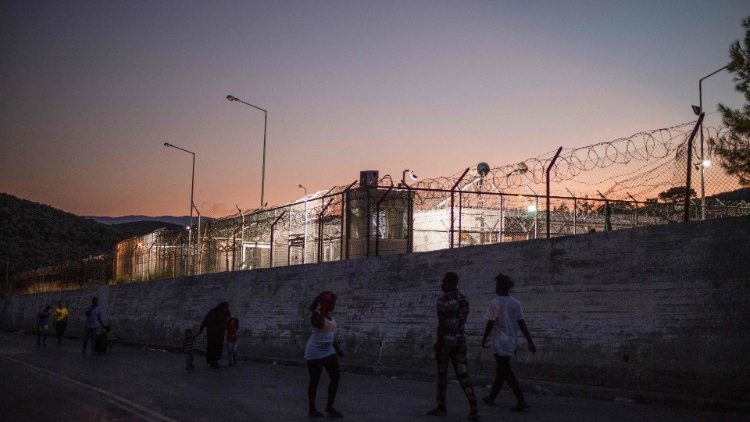 Des réfugiés marchent le long du mur hérissé de barbelés qui ceinture le camp de Moria, sur l'île de Lesbos, le 24 août 2020. Ce camp abriterait envrion 2800 personnes.