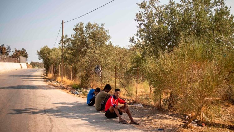 Migrants rest on the road near the burnt Moria refugee camp