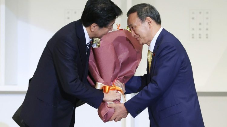 Le futur Premier ministre Yoshihide Suga remet un bouquet de fleurs à son prédécesseur Shinzo Abe, le 14 septembre 2020 à Tokyo.