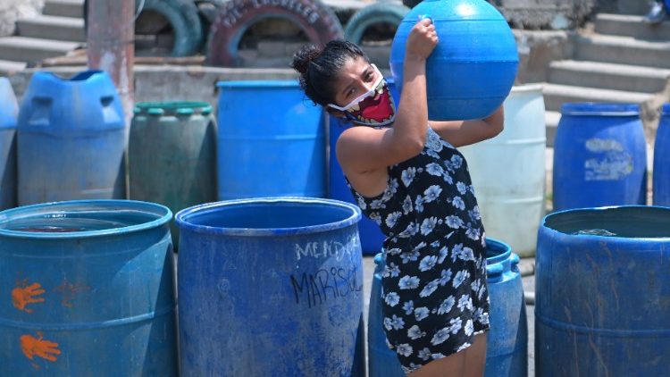 Une Salvadorienne récupérant un bidon d'eau fourni par la Croix-Rouge, le 8 avril 2020 à Ciudad Delgado.
