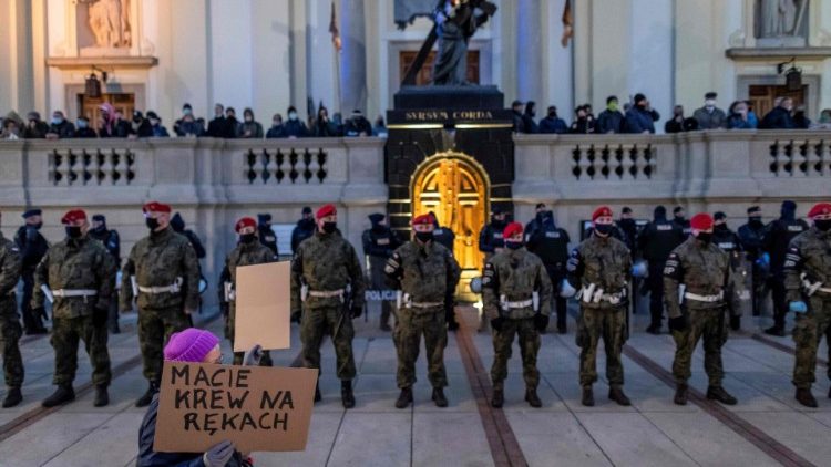 Các tín hữu cầu nguyện trước nhà thờ ở thủ đô Warsaw trong khi quân cảnh và cảnh sát ngăn những người biểu tình