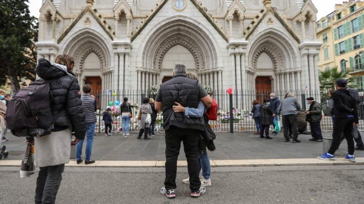 La gente de pie frente a la Basílica de Notre-Dame de Niza para rendir homenaje a las víctimas dos días después de que un atacante con un cuchillo matara a tres personas, dentro de la iglesia.