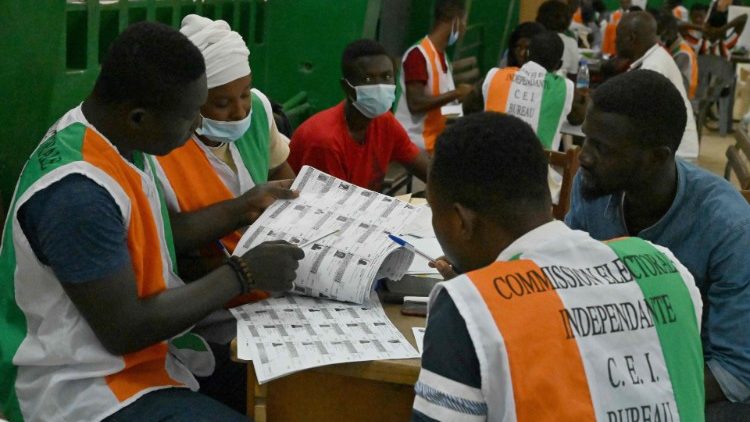 Electoral commission officials checking the voter's roll as they count votes at a polling station in Abidjan, Ivory Coast, after Saturday's election