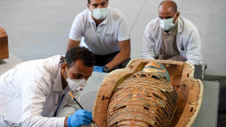 Studiosi intorno alle mummie emerse dai sarcofagi