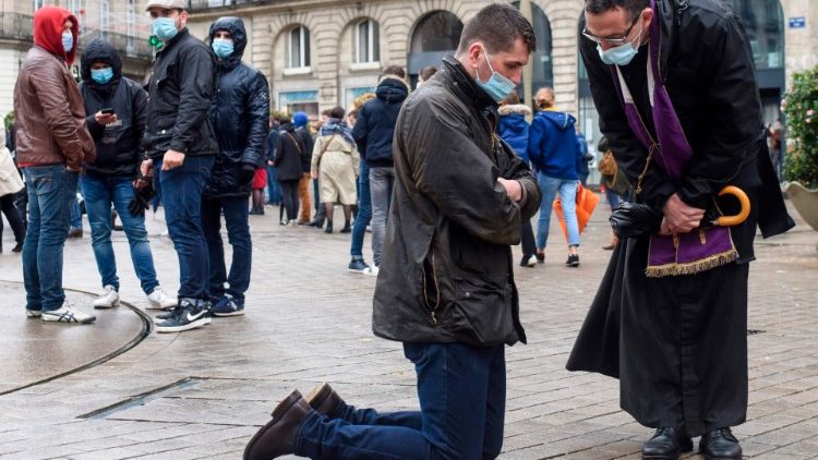O sacerdote ouve a confissão de um católico na França, que vive lockdown