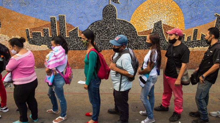 People line up to board a bus next to a mural depicting the National Assembly building in Caracas ahead of parliamentary elections