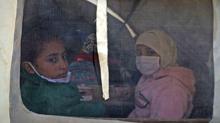 Estudantes sírias protegidas por máscaras em sala de aula improvisada