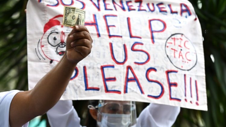 Une infirmière manifeste à Caracas le 9 février 2021, une autre brandissant un dollar, soit le salaire pour deux semaines de travail