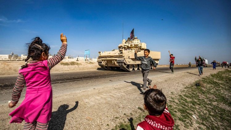 Crianças e patrulha estadunidense em estrada próxima aos campos de petróleo de Suwaydiyah