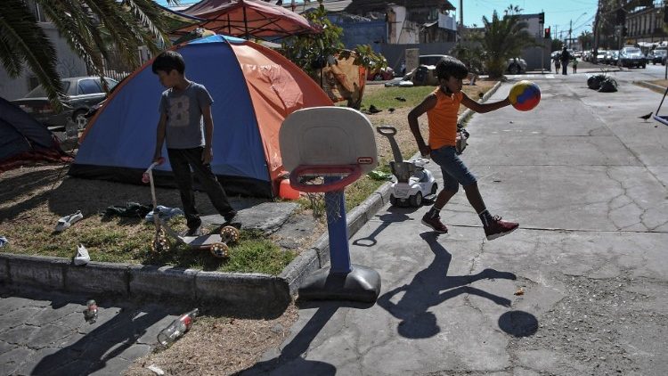 Niños migrantes venezolanos juegan con una pelota en Iquique, Chile, donde cientos de familias permanecen mientras esperan la ayuda del gobierno 