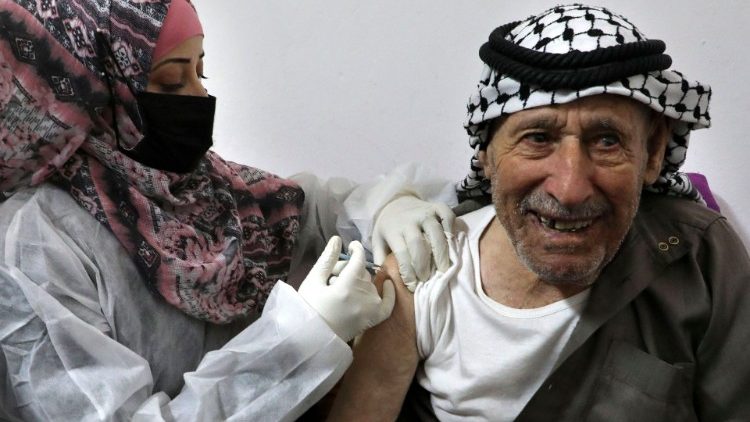 An elderly inhabitant of Hebron in the occupied West Bank receives the innoculation of a Covid-19 vaccine