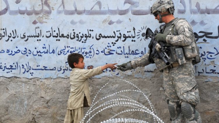 Na foto de 2010, soldado americano dá um presente a uma criança afegã durante uma patrulha