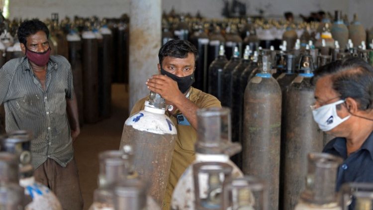 Workers arrange supplies of oxygen to be transported to hospitals in India