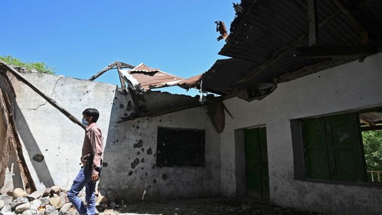 A journalist walks past a damaged school building following cross border shelling on the border between India and Pakistan