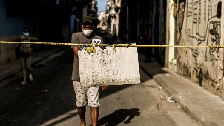 "Fechada por Covid, não passar" diz o cartaz segurado por cubano em rua de Havana