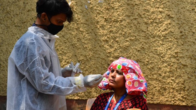 Um profissional de saúde coleta uma amostra de esfregaço de uma mulher para realizar o teste RT-PCR em um centro de quarentena Covid-19 em Mumbai em 3 de maio de 2021. (Foto de INDRANIL MUKHERJEE / AFP)