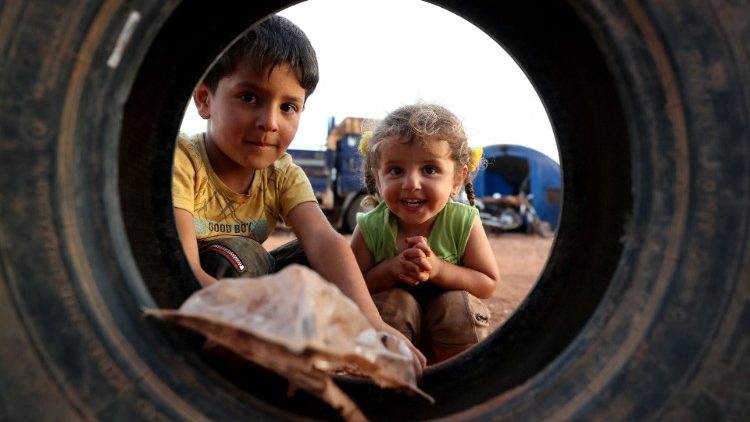 Crianças sírias brincam com um pneu em um campo para deslocados internos na cidade de Maaret Misrin, Província síria de Idlib, no noroeste da Síria, em 8 de maio de 2021. (Foto: OMAR HAJ KADOUR / AFP)