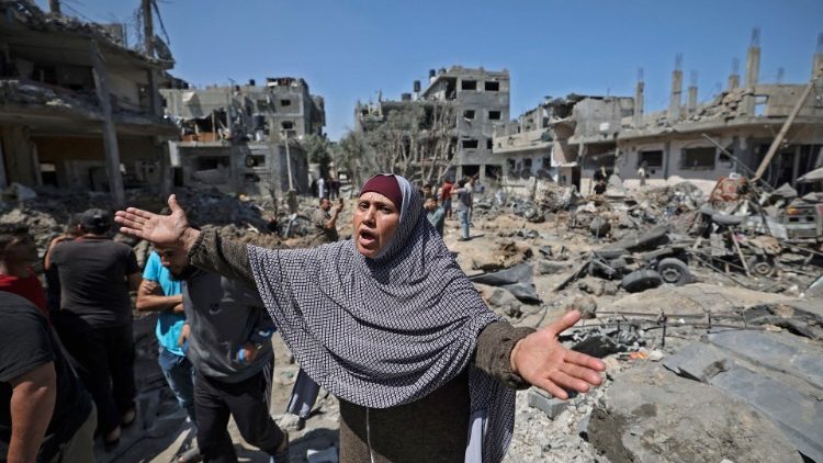 Mulher palestina lamenta destruição em meio a pessoas que observam os danos causados pelos ataques aéreos israelenses, em Beit Hanun, no norte da Faixa de Gaza, em 14 de maio de 2021.  (Foto de MAHMUD HAMS / AFP)