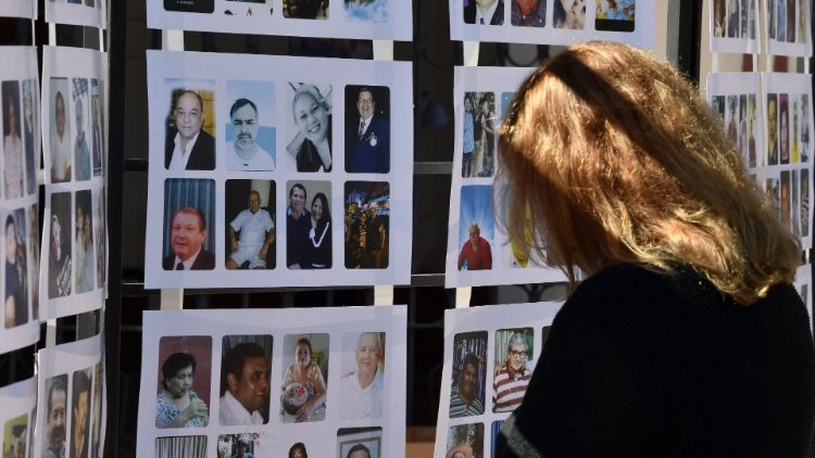 Una mujer mira las fotos de las víctimas del COVID-19 fuera de la Catedral Metropolitana durante una misa en su honor en Asunción el 15 de mayo de 2021. 