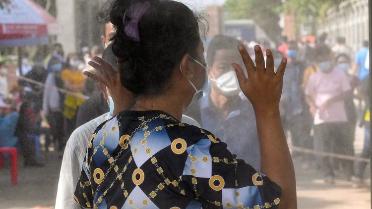 Uma mulher passa por um portão equipado com um spray desinfetante antes de receber a segunda dose da vacina contra o coronavírus Sinopharm Covid-19 da China em um pagode em Phnom Penh.Foto de TANG CHHIN Sothy / AFP)