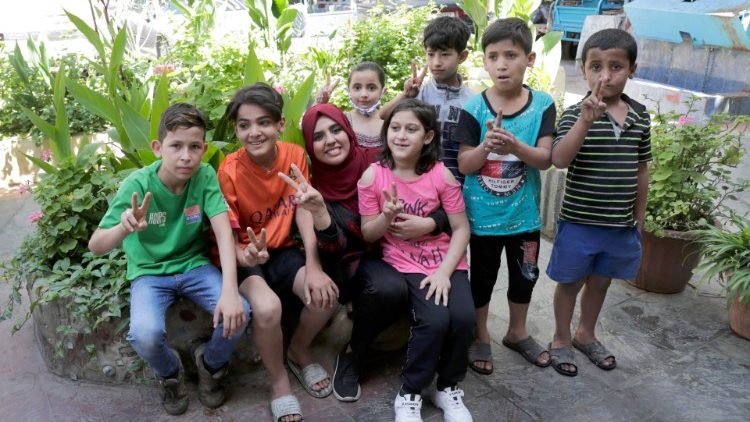 फिलिस्तीनी प्रवासी  कैम्प के बच्चे मीरा कायम के साथ जो उन्हें फिलीस्तीन का इतिहास बताती हैं।