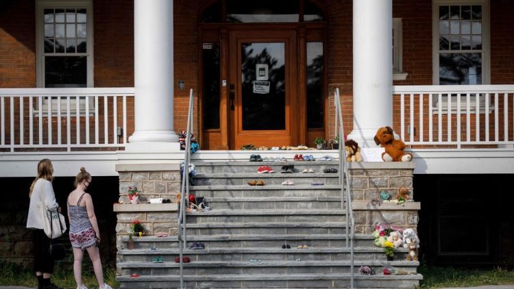 Pessoas ficam em frente a um memorial improvisado para homenagear as 215 crianças cujos restos mortais foram recentemente descobertos em uma vala comum, na entrada principal do Instituto Mohawk, uma antiga escola residencial para crianças da Primeira Nação, em Brantford, Ontário, Canadá