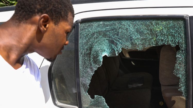 Haitiano observa carro fora da residência presidencial com vidros estilhaçados por tiro