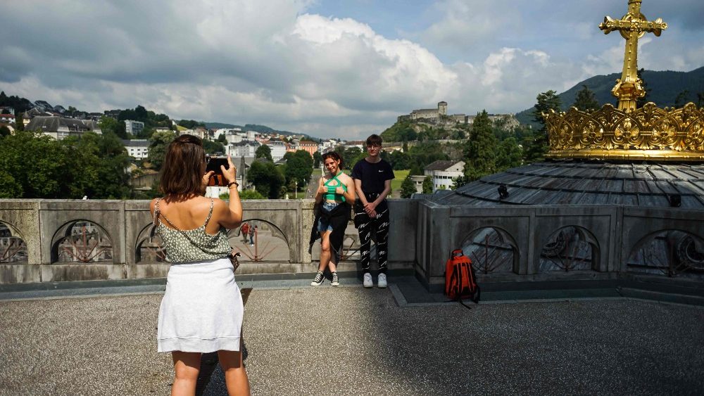 Uma famlia tira uma foto em frente  Baslica do Rosrio enquanto o santurio catlico de Notre Dame de Lourdes d as boas-vindas aos peregrinos aps meses de fechamento devido  pandemia de Covid-19. (Photo by MATTHIEU RONDEL / AFP)