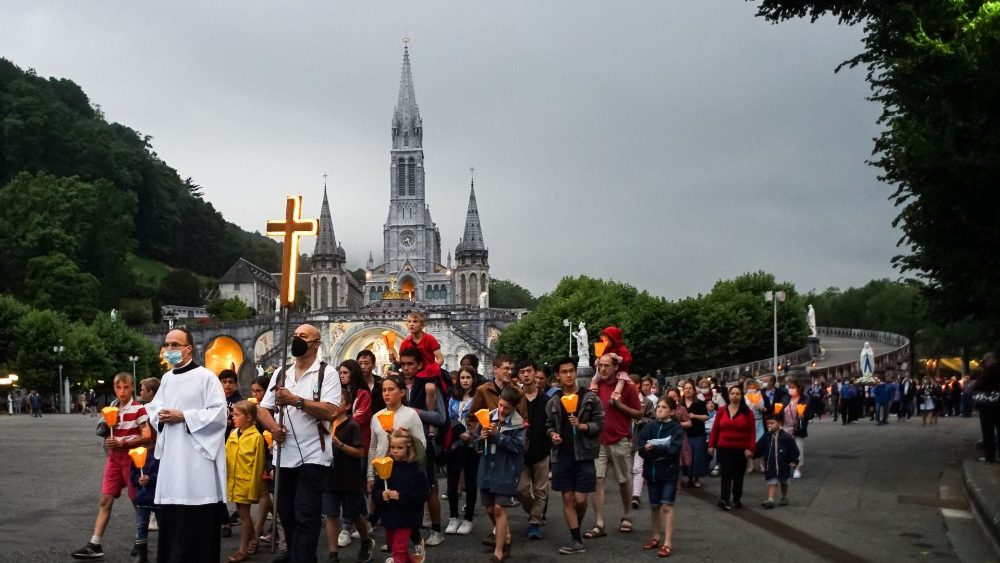 Os peregrinos participam da prociss?o de tochas da Virgem Maria na esplanada do rosrio, pois o santurio catlico de Notre Dame de Lourdes acolhe os peregrinos aps meses de fechamento devido  pandemia de Covid-19 em 3 de julho de 2021; (Photo by MATTHIEU RONDEL / AFP)