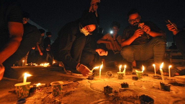 Lidé rozsvěcejí svíčky před nemocnicí al-Hussein v Násiríji, kde při požáru zahynulo nejméně 64 lidí