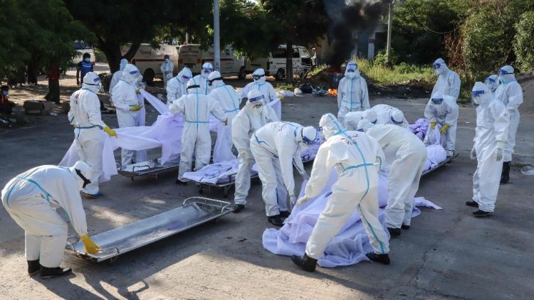 Voluntários usando equipamento de proteção individual (PPE) organizam corpos de pessoas que morreram de coronavírus Covid-19 durante seu funeral em um cemitério em Mandalay. (Foto por AFP)