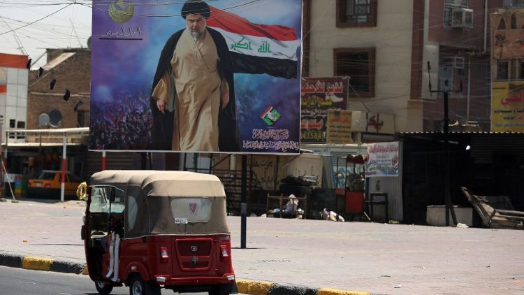 Tuk-tuk devant une affiche du dirigeant chiite Moqtada al-Sadr, ayant annoncé le boycott du scrutin d'octobre, à Sadr City en banlieue est de Bagdad, le 15 juillet 2021. 