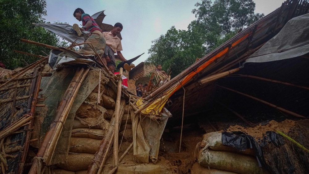 Refugiados Rohingya trabalham em meio aos destro?os de uma casa destruda pelas inunda??es no campo de Balukhali (Foto de Tanbir Miraj / AFP)