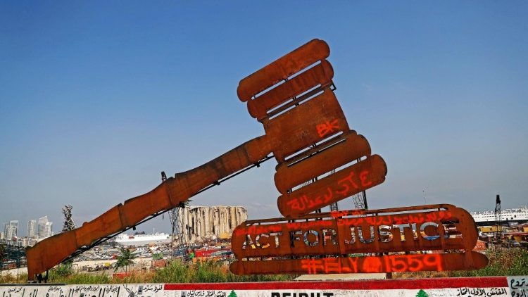 Un monumento a forma di martello che simboleggia la giustizia, di fronte ai silos di grano danneggiati dall'esplosione al porto di Beirut del 4 agosto 2020