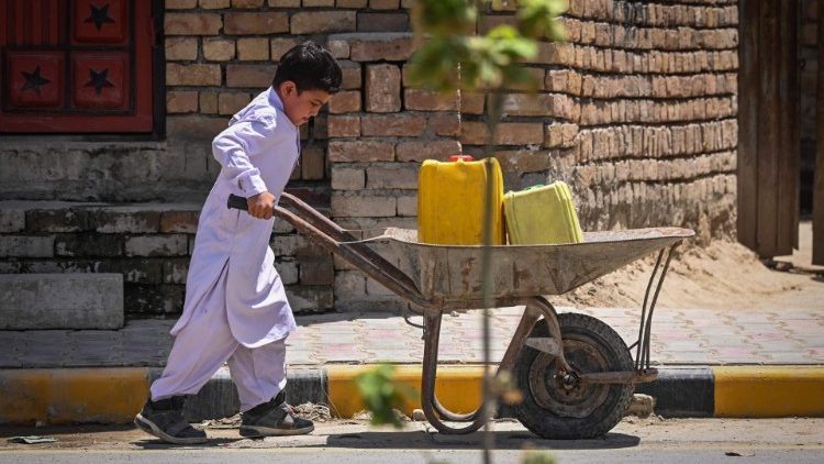 Menino carrega latas de água em um carrinho de mão em Cabul. (Foto de SAJJAD HUSSAIN / AFP)