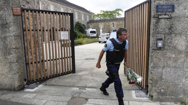 Gendarme francês carrega flores deixadas diante do portão do local onde o sacerdote assassinado residia