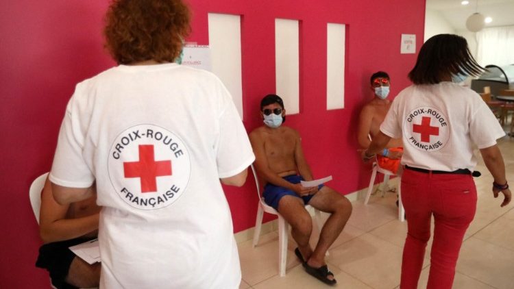 Členové francouzského Červeného kříže vítají rekreanty v očkovacím centru proti Covid-19 zřízeném v kempu 13. srpna 2021 v Argeles-sur-Mer na jihu Francie.