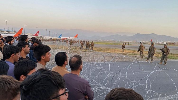 Afegãos se aglomeram no aeroporto de Cabul enquanto soldados estadunidenses montam, em 16 de agosto de 2021. (Foto de Shakib Rahmani / AFP)