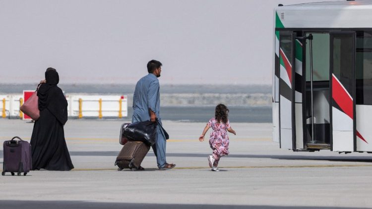 Uma garota corre em direção a um ônibus do aeroporto enquanto pessoas desembarcam de um avião de transporte militar da Força Aérea Real que transportava pessoas evacuadas do Afeganistão e chegavam ao Aeroporto Internacional Al-Maktoum, em 19 de agosto de 2021