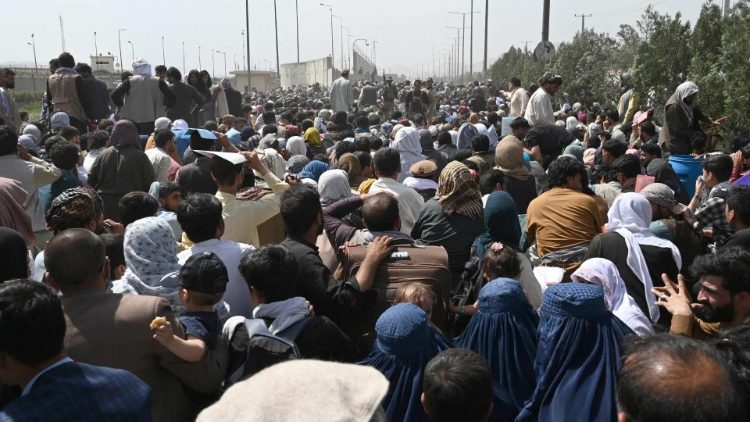 Afghans gather on a roadside near an airport hoping to flee the country following the Taliban takeover of the country