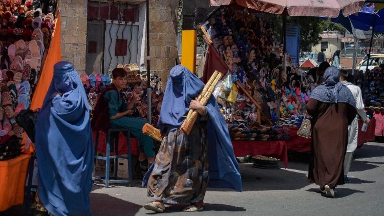 Mulheres afegãs de burca fazem compras numa área de mercado em Cabul, após a tomada militar do país pelos talibãs