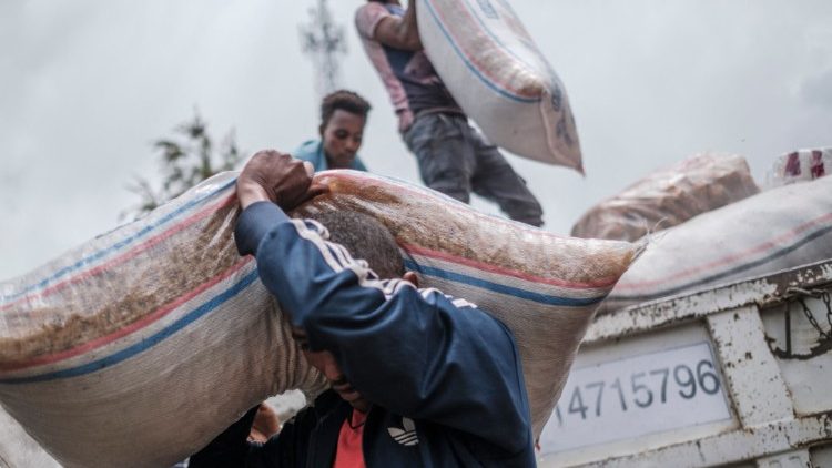 Civis deslocados pelos combates no norte da Etiópia descarregam alimentos e suprimentos de um caminhão, fornecido pela população local, na Escola Addis Fana, onde são temporariamente abrigados, na cidade de Dessie, Etiópia