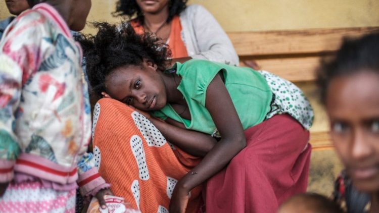 Jovem deslocada pelo conflito no norte da Etiópia está deitada enquanto uma mulher penteia o cabelo na Escola Addis Fana, onde são temporariamente abrigadas, na cidade de Dessie, Etiópia. (Photo by EDUARDO SOTERAS)