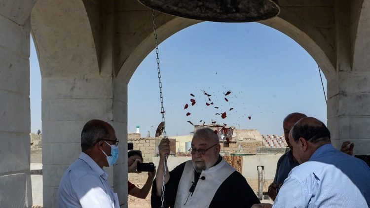 Believers gather as a priest rings the newly inaugurated bell at a Syriac Christian church in Mosul