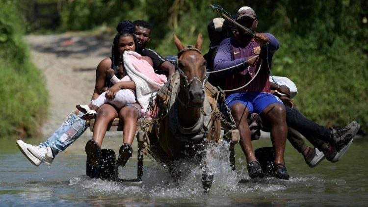 Persone migranti haitiane attraversano un fiume ad Acandi, in Colombia, nel viaggio verso gli Stati Uniti (Raul Arboleda/Afp)