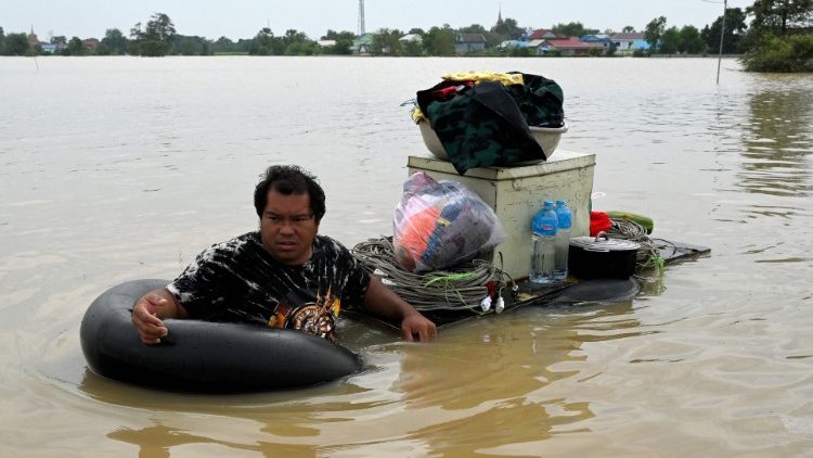 Vietnamita transporta mercadorias em local inundado por enchentes nos arredores de Phnom Penh, em 27 de outubro de 2021, após fortes chuvas de monções. (Foto de TANG CHHIN Sothy / AFP)