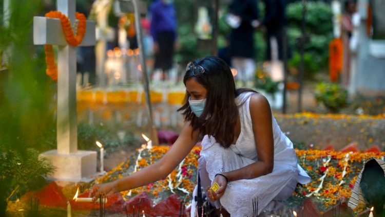Eine Christin in Bangladesch zündet am Grab von Angehörigen eine Kerze an