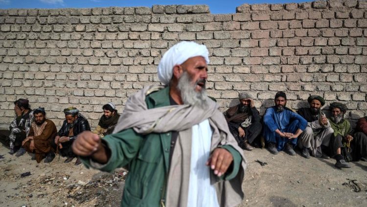  Unos hombres esperan mientras las mujeres (no en la foto) y sus hijos aguardan que los miembros del personal de Médicos Sin Fronteras comprueben si hay signos de desnutrición, en un campo de desplazados internos en las afueras de Herat.